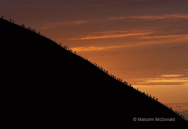 Tourists begin their climb to the summit just after sunrise, Uluru NP, NT